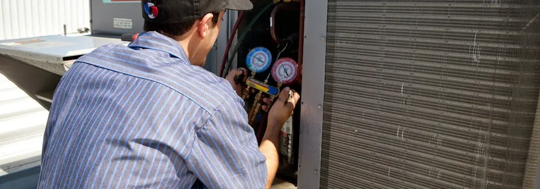 HVAC technician servicing a condenser unit in Bow